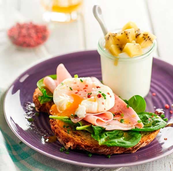 Gepocheerd ei met gele kiwi, ham en spinazie