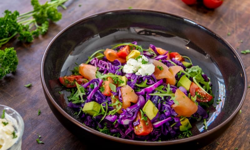 Paarse spitskoolsalade met gerookte zalm, rucola, tomaat en avocado